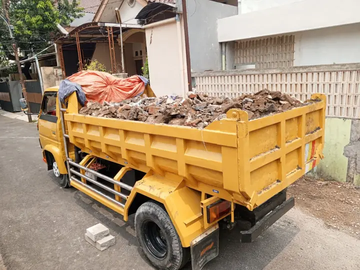 Truk bak kuning berisi puing bongkaran parkir di depan rumah